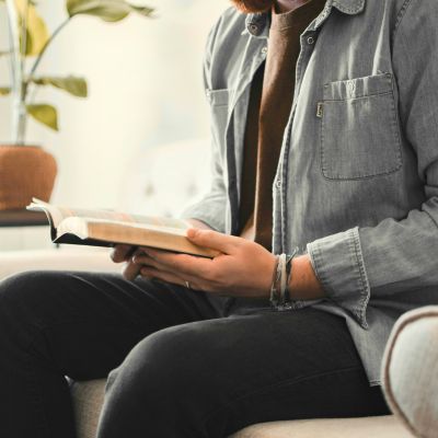 Person sitting on a couch reading a book.