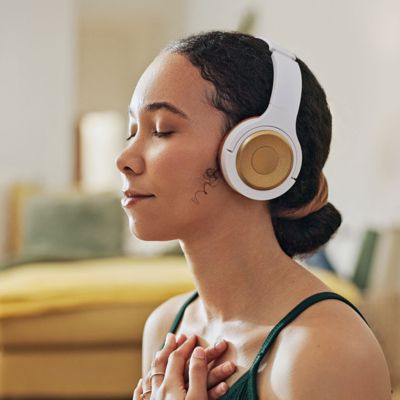 Person wearing white and gold over-ear headphones.